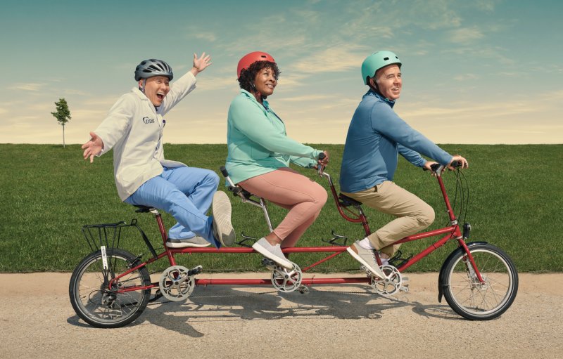 A dentist and two older adults enjoying a tandem bike ride, illustrating a carefree view about dental insurance in retirement