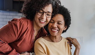 Mother and adult daughter smiling together at home, reflecting family dental insurance benefits.