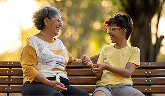 Older adult and child sharing a moment on a park bench, showing intergenerational dental care support.