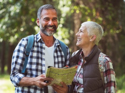 Smiling man and woman in casual clothing, looking like they're about to go on a hike